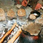 Platte koekjes bakken op stenen rond het vuur. (klik voor een uitvergroting)